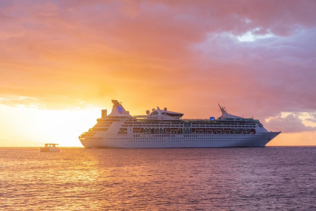 A majestic cruise ship sails at sunset off the coast of Grenada, showcasing luxury travel.