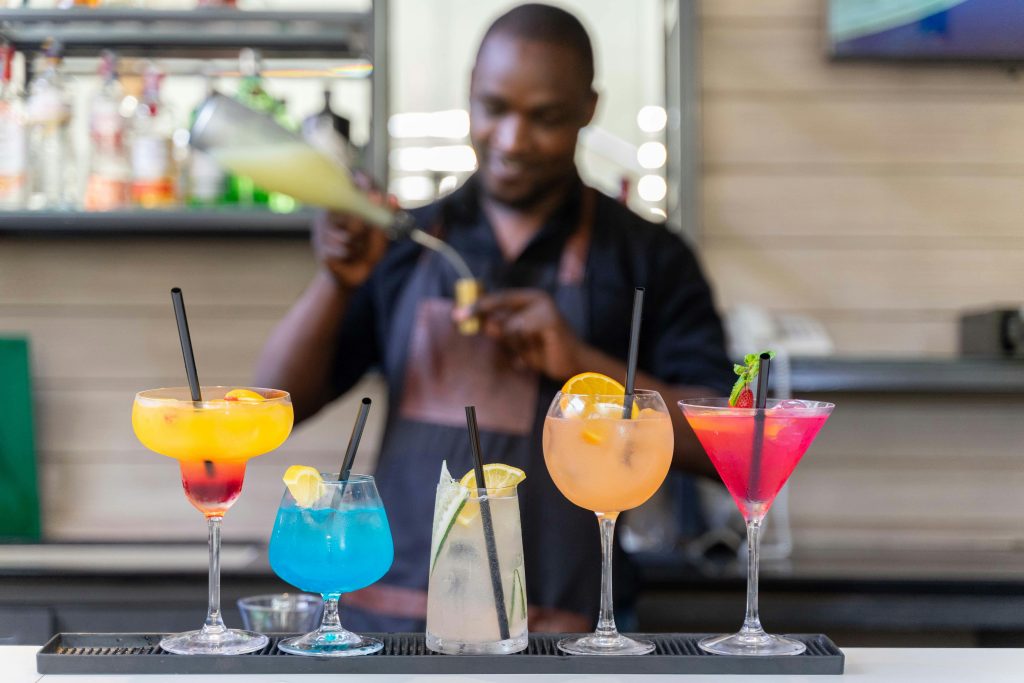 Bartender expertly crafting vibrant cocktails at a modern bar setting, showcasing colorful drinks.