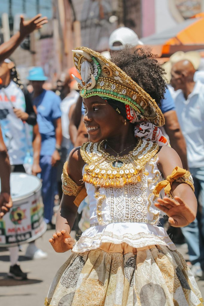 A young girl in traditional attire celebrates amidst a lively street festival in Salvador, Bahia, Brazil.