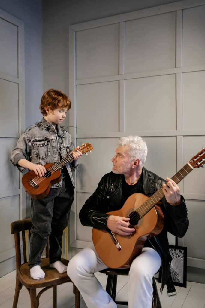 Grandfather teaching grandson guitar at home, fostering family bonding and musical learning.