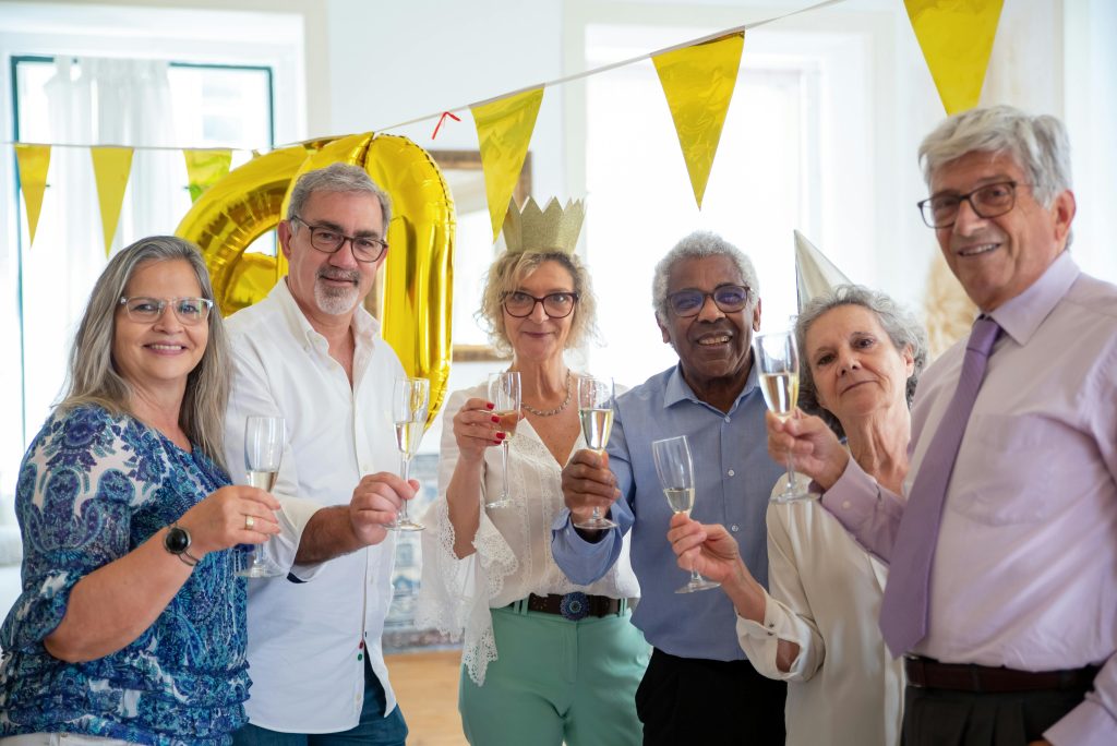 Elderly friends celebrating indoors with champagne, sharing smiles and joy at a festive party.