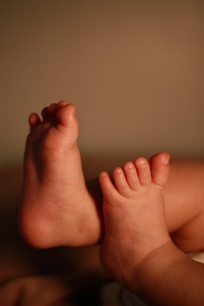 A close-up shot of an infant's adorable feet against a warm background.