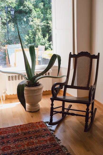 A cozy living space featuring a vintage rocking chair and a potted plant by a sunlit window.