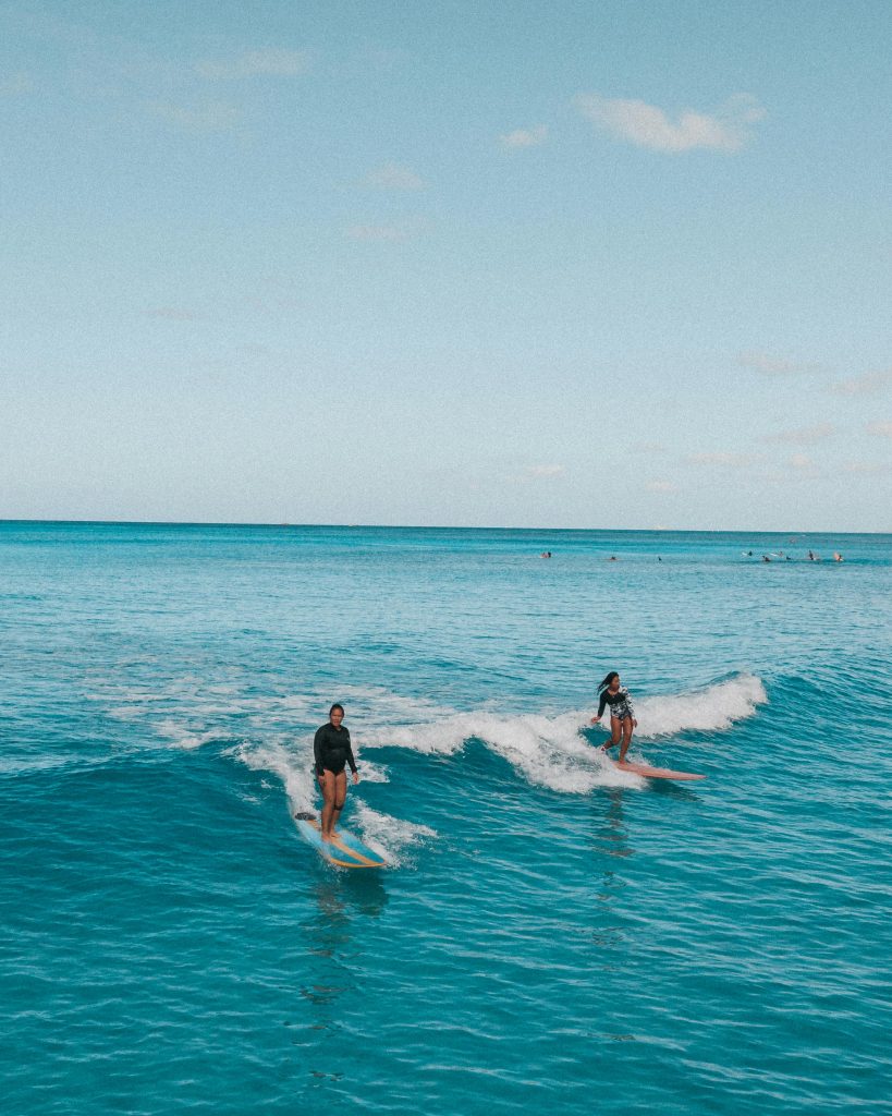 Two surfers enjoying the waves in Honolulu, Hawaii under a clear blue sky.