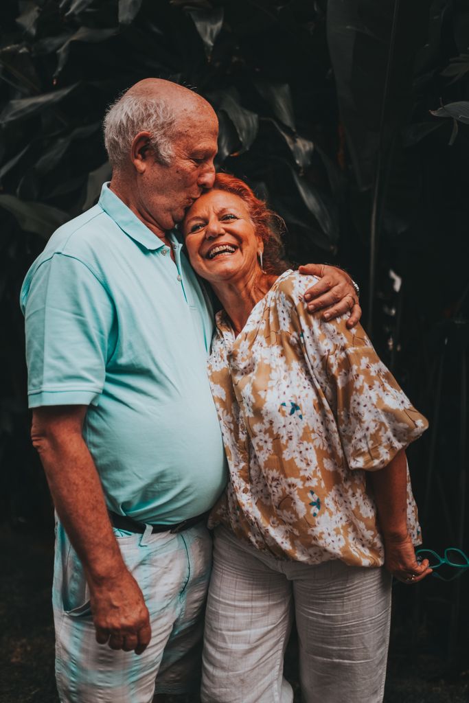 Joyful senior couple hugging and kissing outdoors showcasing love and happiness.