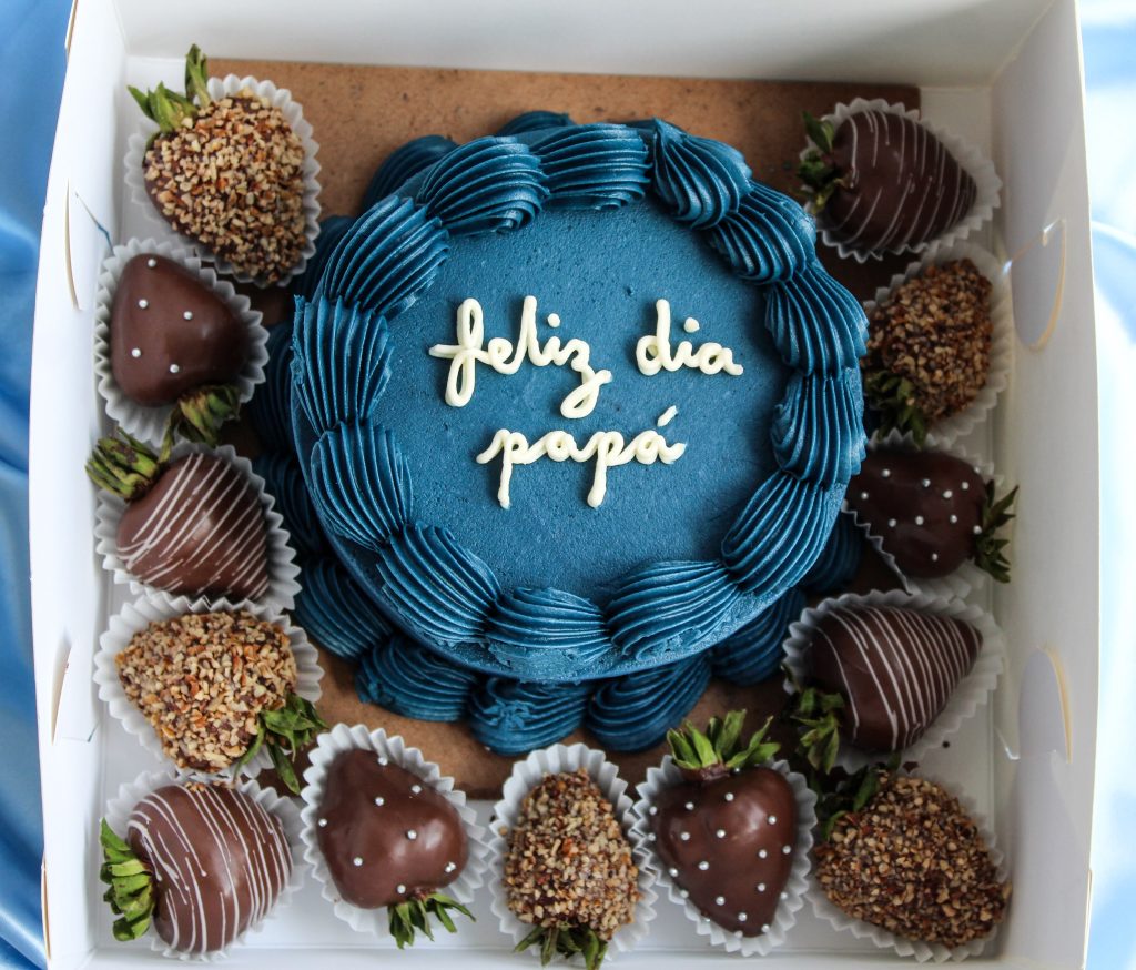 A festive blue cake for Father's Day with chocolate-covered strawberries.