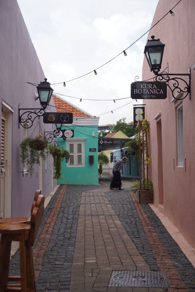 Colorful alley in Willemstad with vibrant walls and street signs, capturing Curaçao's charm.